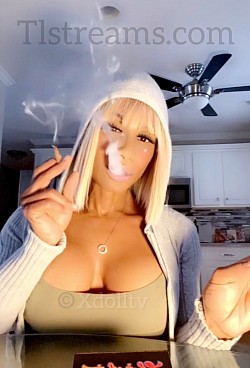 Blonde woman smoking and posing seductively in a softly lit kitchen, creating a sensual adult-lifestyle aesthetic.